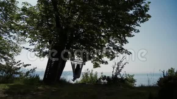 Garda湖畔的吊床上躺在树荫下女孩的剪影长期射击视频的预览图