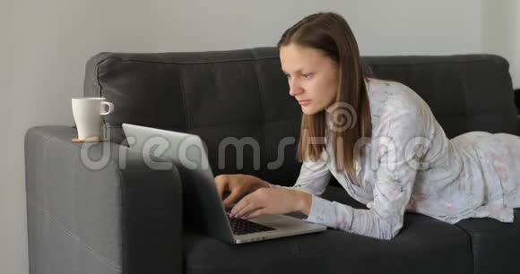 关注千禧一代女性自由职业者远程在线工作阅读新闻在舒适的沙发远程在家女人咳嗽视频的预览图