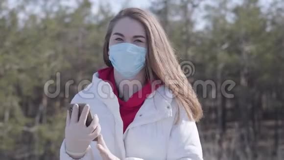 黑发年轻女子戴着面罩和防护手套在电话上交谈的肖像布鲁内特高加索女孩视频的预览图