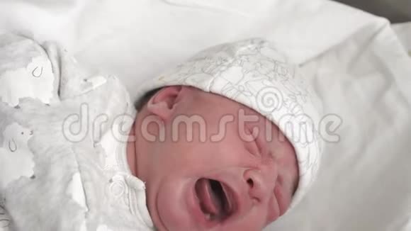 在新生儿出生的早期在医用玻璃床上为新生儿做特写哭泣和做脸A视频的预览图