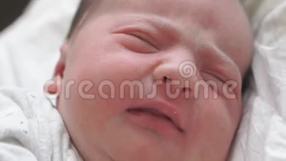 特写一个新生婴儿的脸在早期谁醒来并睁开眼睛一个刚出生的婴儿在做鬼脸视频的预览图