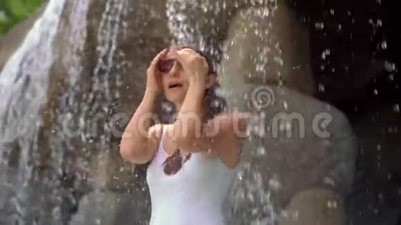 一位年轻女子在热带度假胜地有温泉瀑布和游泳池有热水慢动作视频的预览图