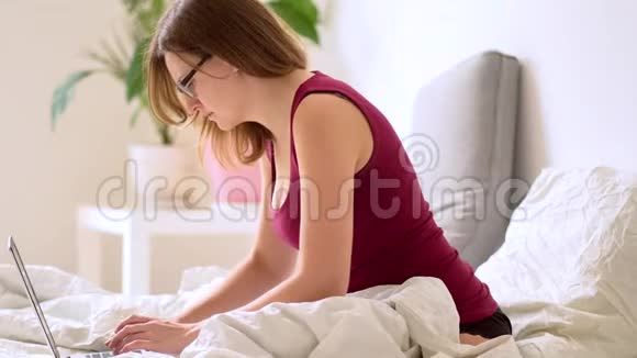 一个女人在卧室里用笔记本电脑工作视频的预览图