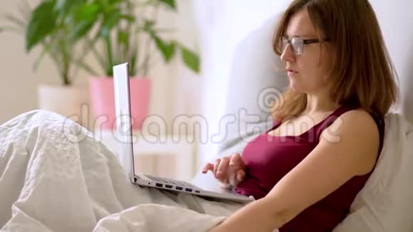 一个女人在卧室里用笔记本电脑工作视频的预览图