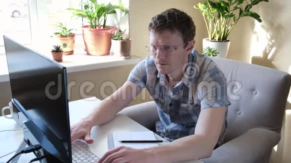 程序员在家工作远程家庭办公室一个戴眼镜的人看着显示器远程工作概念视频的预览图