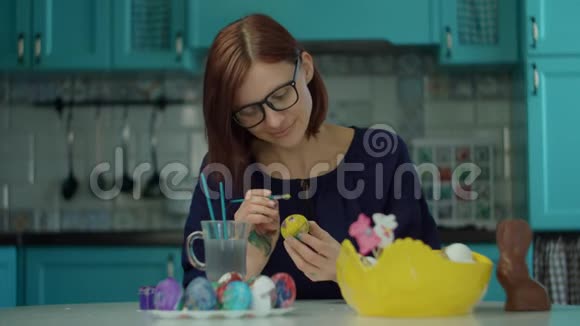30岁的年轻妈妈在家里的蓝色厨房里画复活节彩蛋准备复活节彩礼的快乐女人视频的预览图