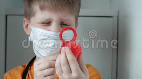 一个戴着医用口罩的男孩透过玩具放大镜检查病毒视频的预览图