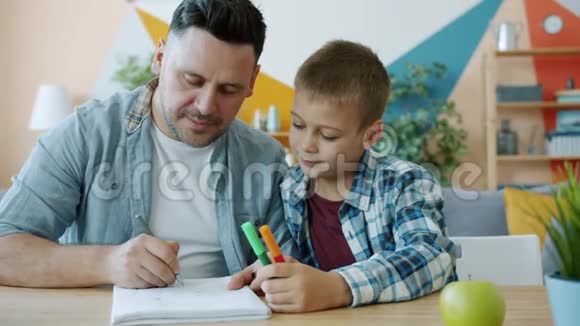 关心父亲的有创造力的人一边画画一边看着孩子坐在办公桌前视频的预览图