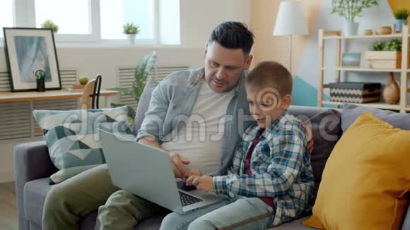 父亲和孩子在公寓玩电脑游戏玩笔记本电脑视频的预览图