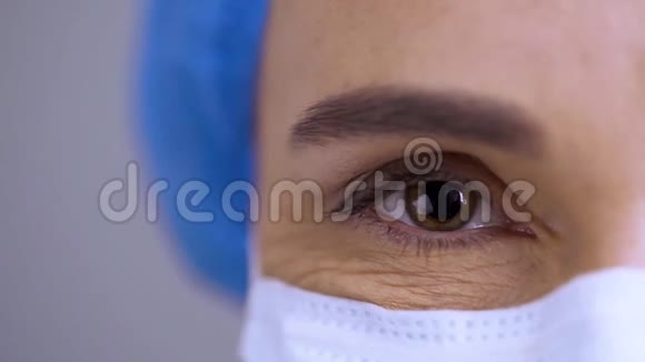 外科医生的特写他的脸在柜子的背景上一位戴着白色面具的贴身女医生的画像视频的预览图