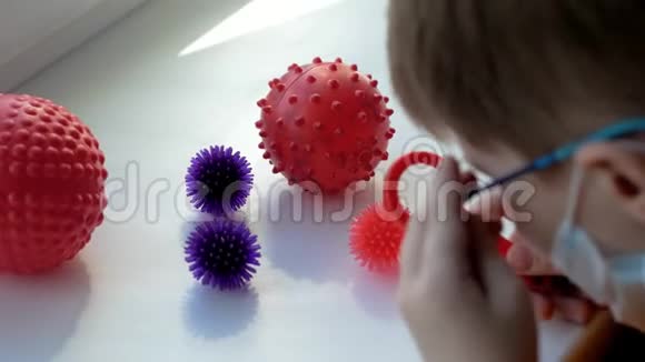 一个戴着面具的男孩拿着玩具放大镜看球像冠状病毒一样视频的预览图