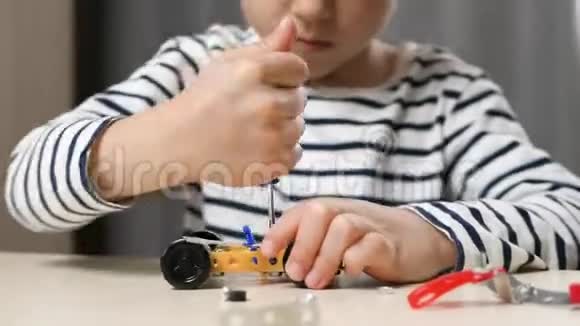 幼儿与施工员一起玩坐在桌旁一个学前男孩收集一个汽车模型发展视频的预览图
