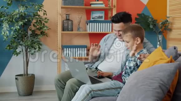 父亲和儿子用笔记本电脑打在线视频电话显示竖起大拇指视频的预览图