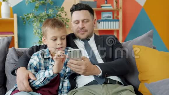 商人和小男孩使用智能手机在家享受在线内容视频的预览图