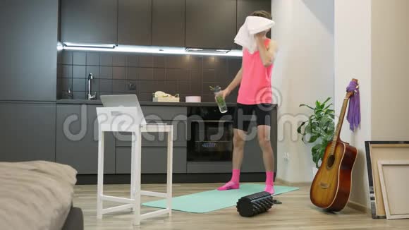年轻的白种人穿着粉色运动服饮水后在家进行网上健身训练80的搞笑男运动员视频的预览图