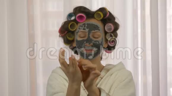 女人脸上戴着清洁面具看着摄像机年轻女性在家接受护肤治疗的肖像女人美丽视频的预览图