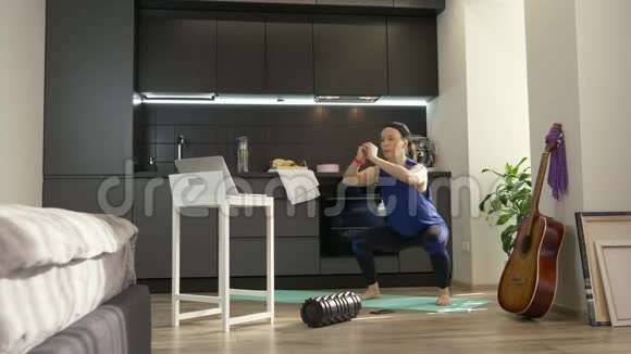 强壮美丽的健身女性穿着运动服在家里蹲着在笔记本电脑上使用在线应用程序女人在做什么视频的预览图