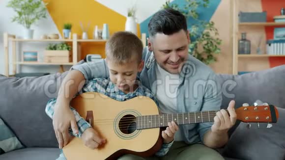 幸福的家庭父子在公寓里弹吉他一起玩视频的预览图