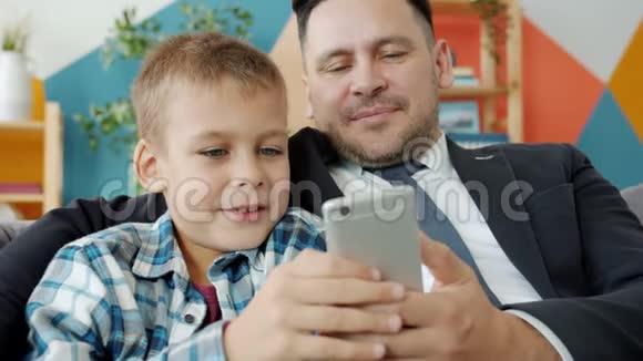 可爱的孩子使用智能手机父亲商人在家触摸屏幕视频的预览图