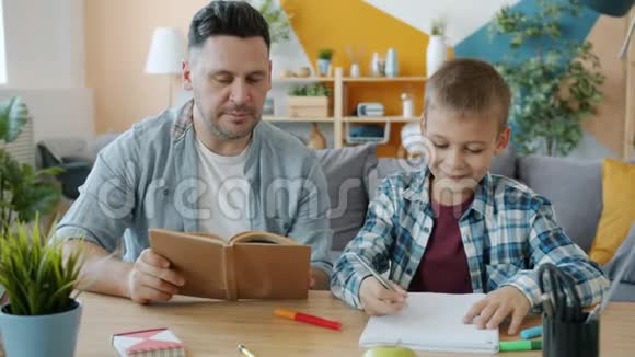 有创意的孩子一边画画一边父亲一边看书一边坐在书桌旁视频的预览图