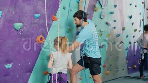 父亲和女儿在攀岩运动中交谈准备爬上人造墙视频的预览图