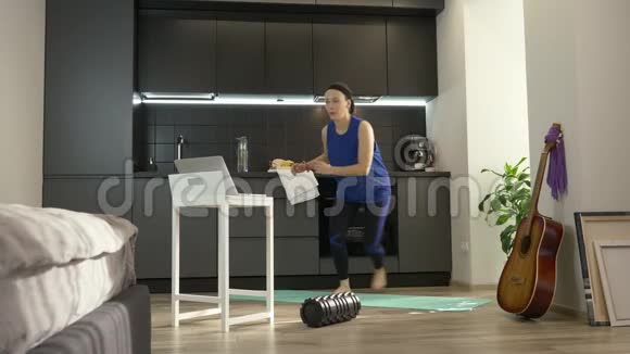 女孩在家在线培训使用笔记本电脑上的应用程序女人在厨房做有氧健身运动女运动员视频的预览图