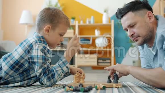父亲和儿子下棋的肖像把棋子放在船上准备比赛视频的预览图