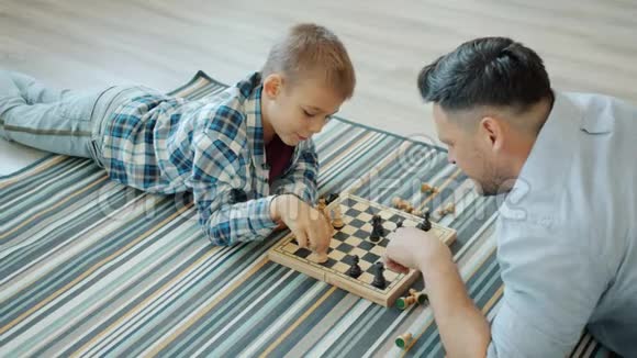 聪明的孩子和父亲一起玩棋盘游戏在家里有空闲时间视频的预览图