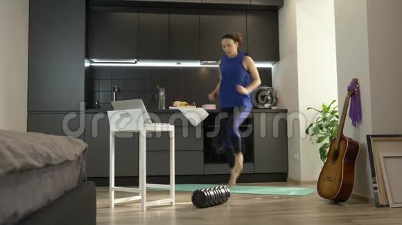 健康女性在冠状病毒检疫期间使用笔记本电脑上的应用程序在线做运动健身锻炼女性视频的预览图