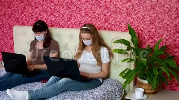 从家里远程工作两名白种人妇女一名年轻的金发女郎和一名戴防护口罩的成年人正在研究视频的预览图