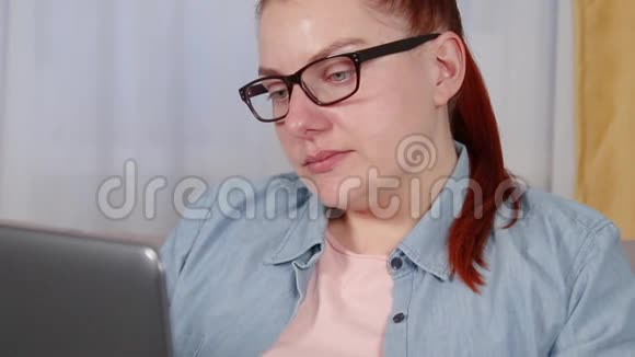 漂亮的年轻女子坐在客厅里用手提电脑工作视频的预览图