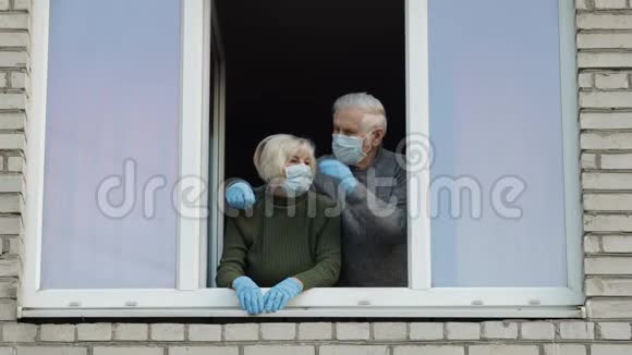 老爷爷奶奶在隔离的窗户里呆在家里冠状病毒视频的预览图