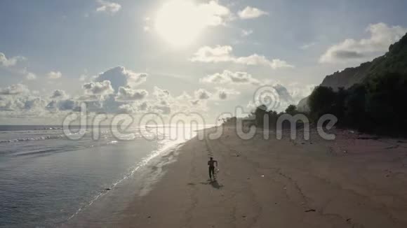 空中观景运动员独自在沙滩海洋和日落的背景上跑步视频的预览图