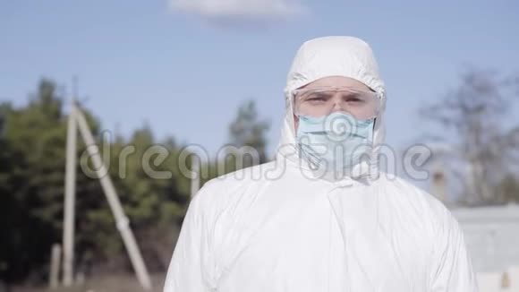 年轻自信的白种人穿着白色安全套装在郊区行走戴面罩和防护的严重病毒学家视频的预览图