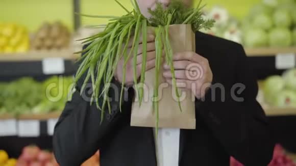 无法辨认的白人男人闻着纸包里的和葱把一堆绿色植物伸向镜头视频的预览图