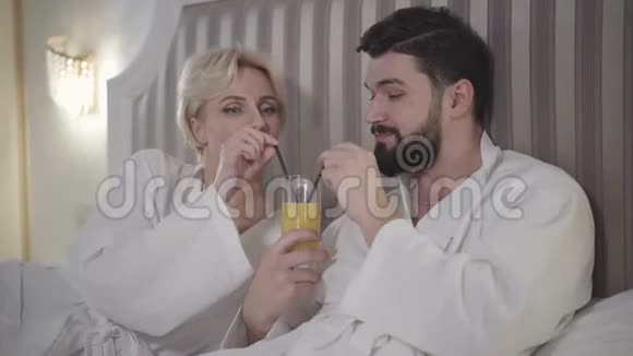 一杯橙汁的快乐白种人男女肖像快乐的情人彼此相视视频的预览图