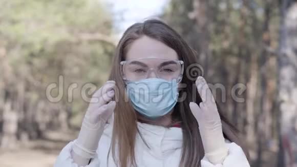 年轻女子摘下防护眼镜和面罩对着镜头微笑布吕内特白人女孩视频的预览图