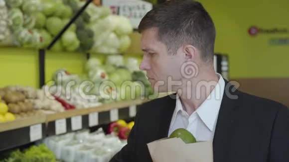 一位自信的白种人成年男子在杂货店里选择柚子把柑橘类水果装进袋子里然后离开视频的预览图