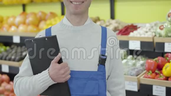 无法辨认的微笑白人男子站在杂货店与文件夹穿蓝色制服的成人超市员工视频的预览图
