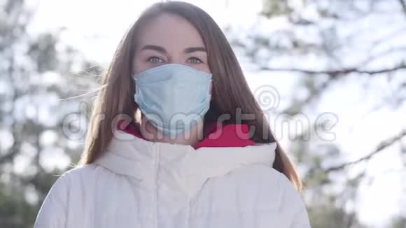 戴着面具的年轻女子站在户外晒太阳布吕内特高加索地区女孩视频的预览图