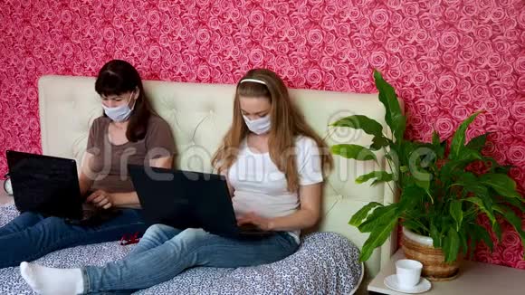 从家里远程工作两名白种人妇女一名年轻的金发女郎和一名戴防护口罩的成年人在笔记本电脑上工作视频的预览图