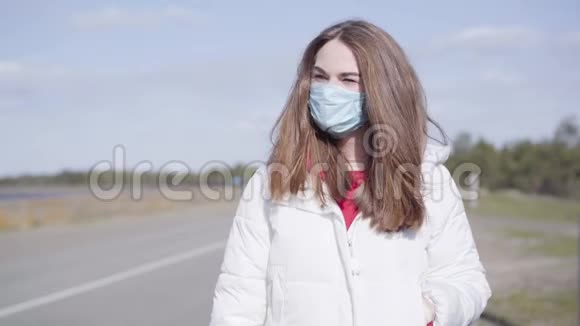 白种人年轻女子戴着防护面罩站在空旷的郊区道路上的肖像美丽的黑发女孩视频的预览图