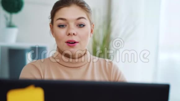在办公室的笔记本电脑上有视频通话的积极女孩视频的预览图