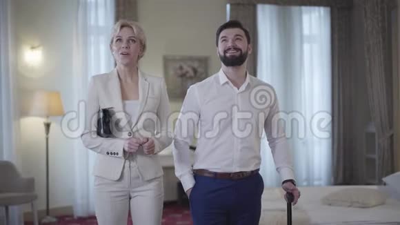 兴奋的白种人夫妇在豪华的酒店房间里环顾四周朝不同的方向离去的画像视频的预览图