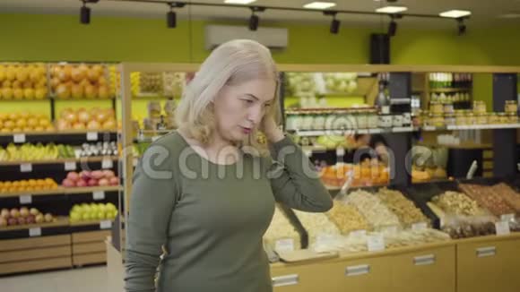 高加索裔金发女人在杂货店买东西家庭主妇在超市购买产品的肖像零售视频的预览图