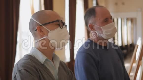 两个戴着医疗面具的人站在画廊里看展览视频的预览图