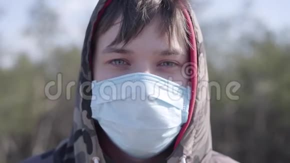 户外防护面罩的年轻白种人的特写脸用灰色眼睛的深色男孩画像视频的预览图