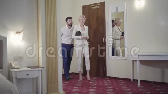 积极的高加索夫妇带着旅行袋进入酒店房间交谈抵达的满意酒店客人的肖像视频的预览图