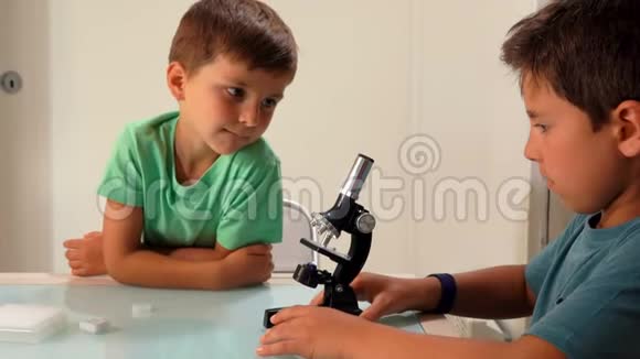 两个黝黑可爱的兄弟姐妹透过显微镜看视频的预览图