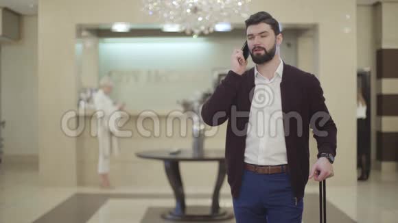 年轻的高加索商人在豪华酒店进行电话交谈的肖像带胡子的黑发男子视频的预览图
